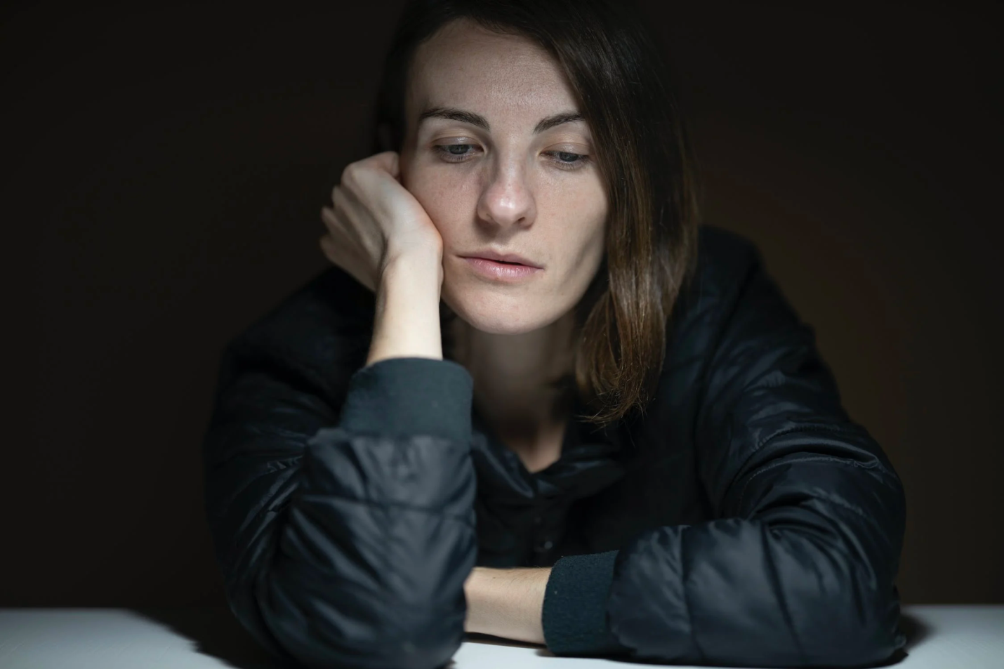 A woman with poor hormonal health looks depressed and tired while seated at a table