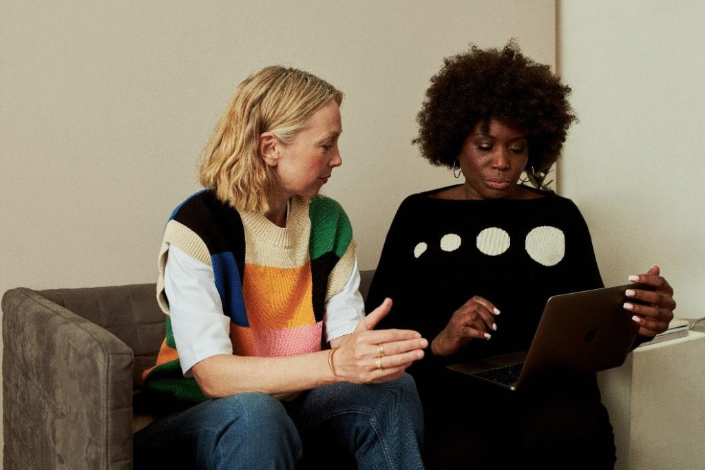Two women sitting on a couch looking at a screen