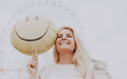 a woman smiling while holding a balloon