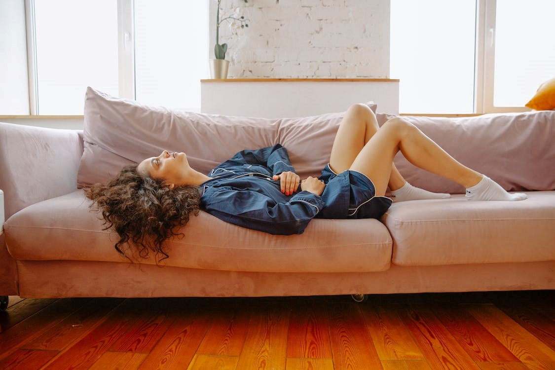 Woman holding her stomach while lying down on a couch